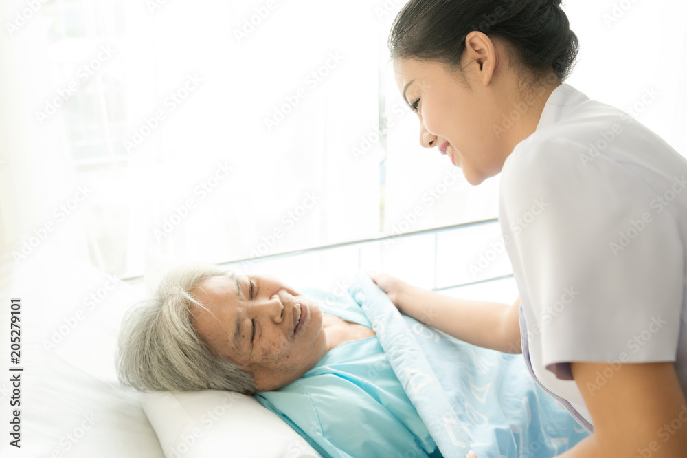Nurse with patient. Routine health check and putting elderly patient to bed. Female nurse with senior chinese woman. Nurse with patient. Routine health check and putting elderly patient to bed. Female nurse with senior chinese woman.