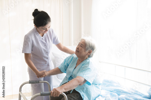 Nurse with patient. Routine health check and assisting elderly patient to walk. Female nurse with senior chinese woman.