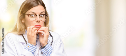 Young doctor woman, medical professional terrified and nervous expressing anxiety and panic gesture, overwhelmed