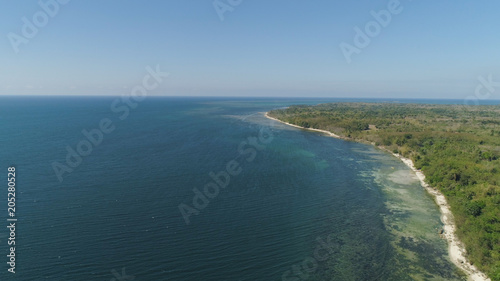 Aerial view of Coastline landscape with rocky beach with palm trees, blue water on tropical island. Flight over a wild beach. Philippines, Luzon.