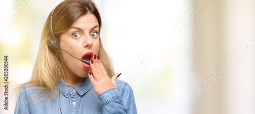 Tableau sur toile Consultant of call center woman in headphones covers mouth in shock, looks shy,