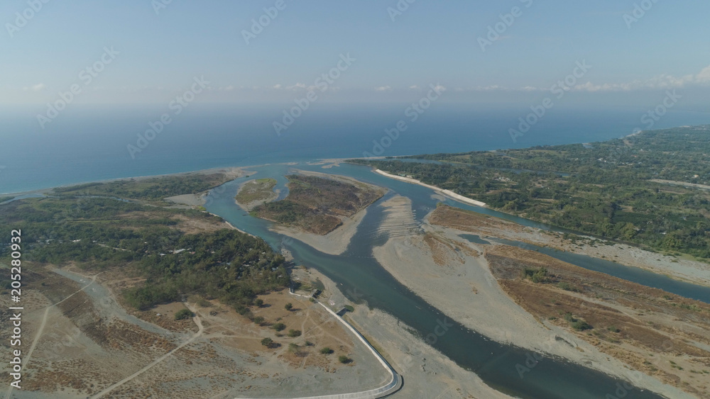 Aerial view of rver flowing into the sea in Philippines,Luzon. ropical landscape with sandy coast and river among farmer fields flowing into the blue ocean