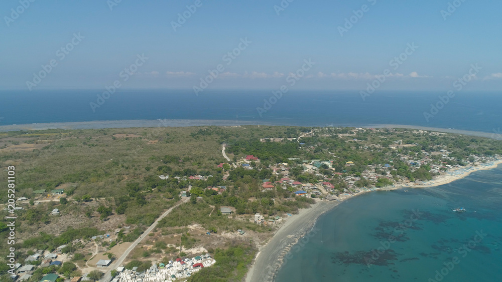 Tropical island with sandy beach, palm trees. Aerial view of coast island Pinget with colorful reef. Seascape, ocean and beautiful beach. Philippines, Luzon. Travel concept.