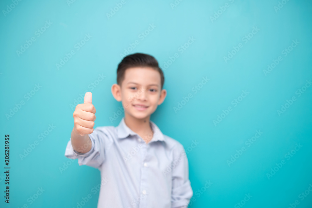 Young boy isolated in blue. Handsome early teenage boy portrait. Happy smile thump up pose. Young boy isolated in blue. Handsome early teenage boy portrait. Happy smile thump up pose.