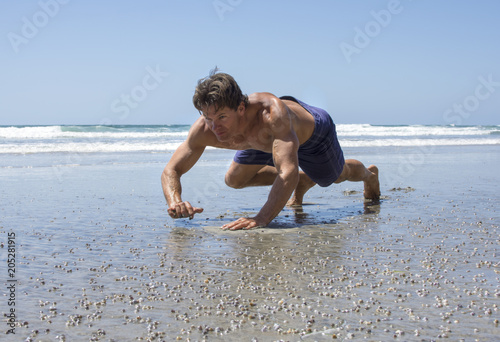Man doing beach bear crawl workout