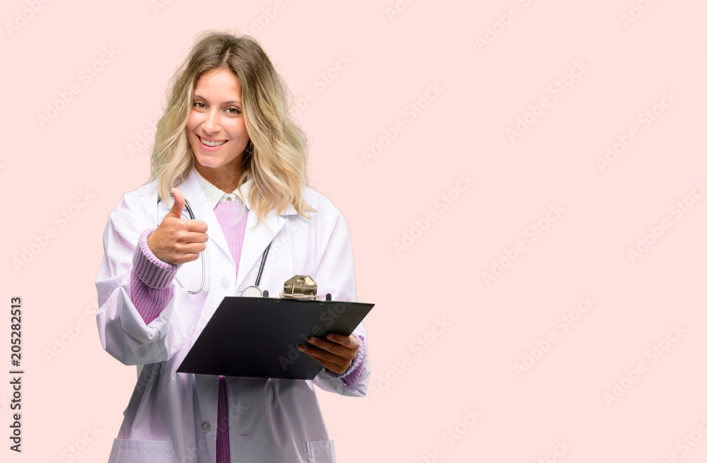 Young doctor woman, medical professional smiling broadly showing thumbs up gesture to camera, expression of like and approval Young doctor woman, medical professional smiling broadly showing thumbs up gesture to camera, expression of like and approval