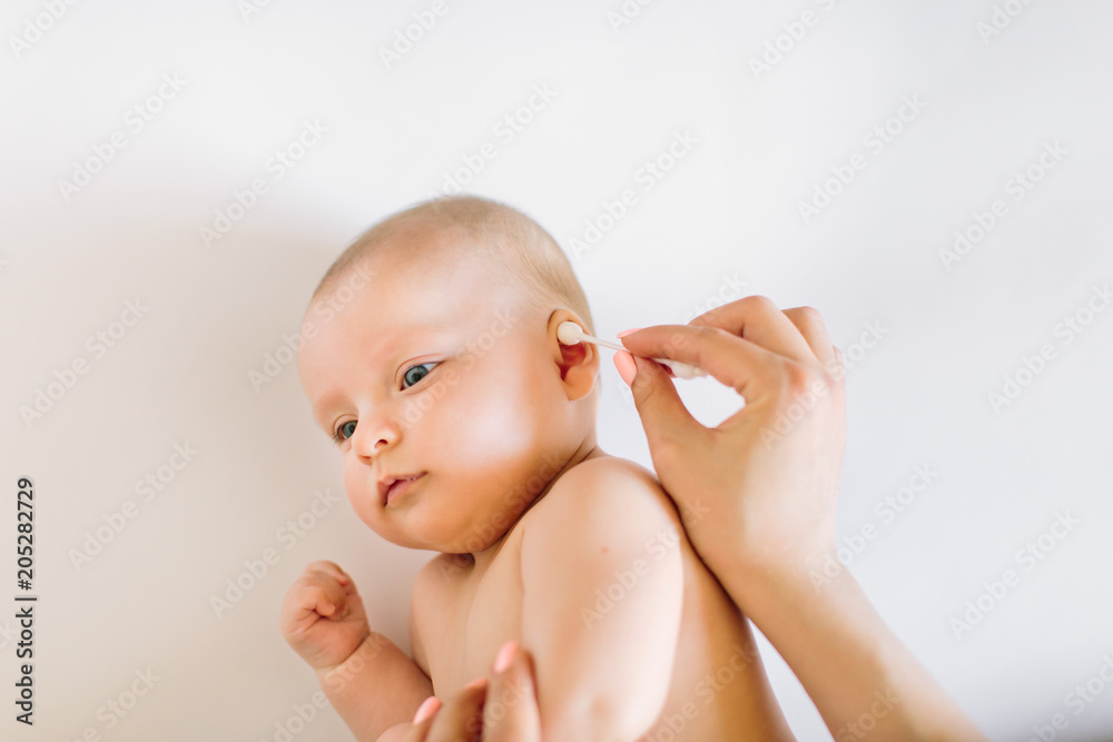 Mother hand cleaning baby ear with cotton swab Mother hand cleaning baby ear with cotton swab