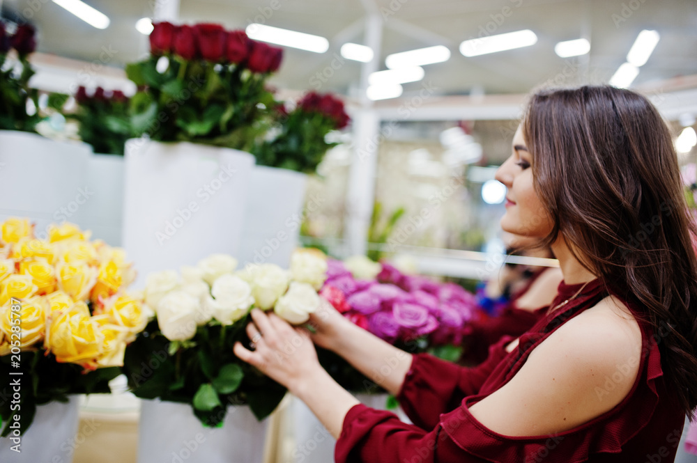 Brunette girl in red buy flowers at flower store.
