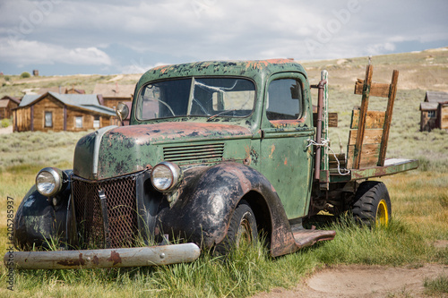 Uraltes , durch Erosion in den Boden eingesunkenes grünes Autowrack eines Lastwagen in einer Geisterstadt der USA, in einer staubigen und verlassenen Ebene gerahmt mit sanften Hügeln.