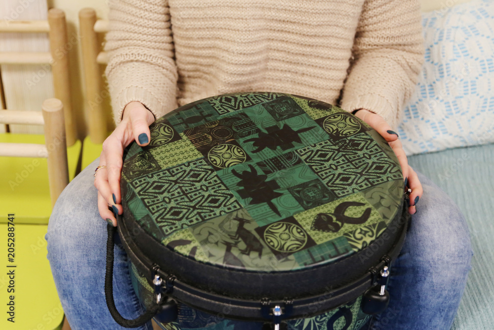 Teacher plays jenga drum in a montessori music therapy classroom,  hands close up