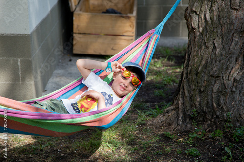 A kindergartener hanging out in a hammock in an alternative school yard © craftykat