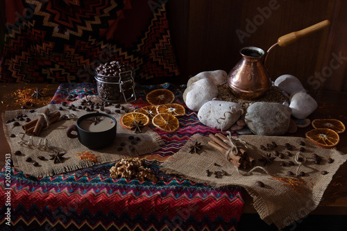 Сoffee table with the cezva on sand and patterned tablecloth in Oriental style. Scattered coffee beans and spices