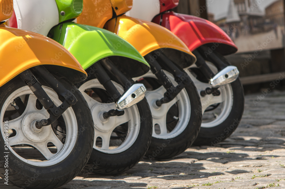 three mopeds painted in red green yellow colors