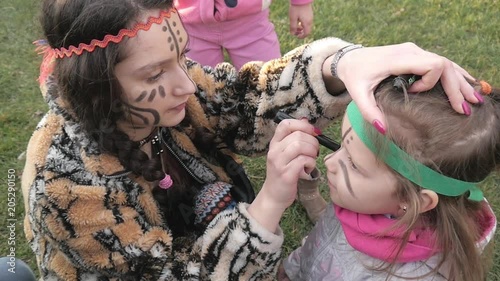 Children paint faces with black Pencil in Indian Mask way playing indians photo