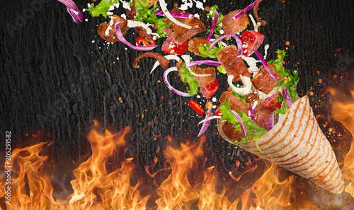 Turkish Kebab yufka with flying ingredients and flames.