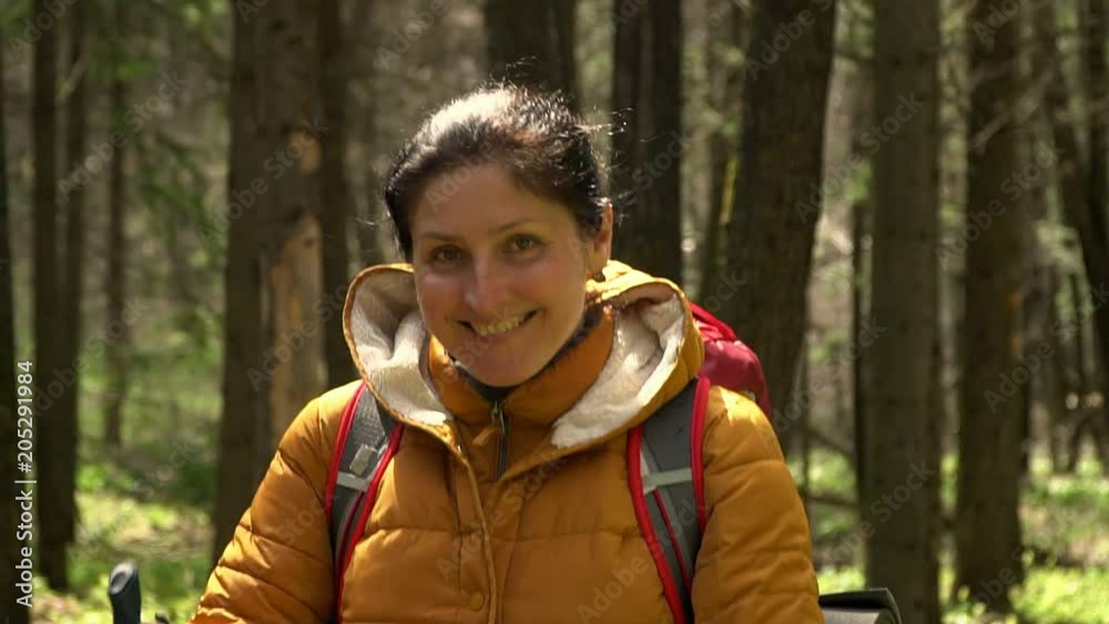 120 fps. The woman with a red backpack travels around the forest road. Scandinavian walking. 120 fps. The woman with a red backpack travels around the forest road. Scandinavian walking.