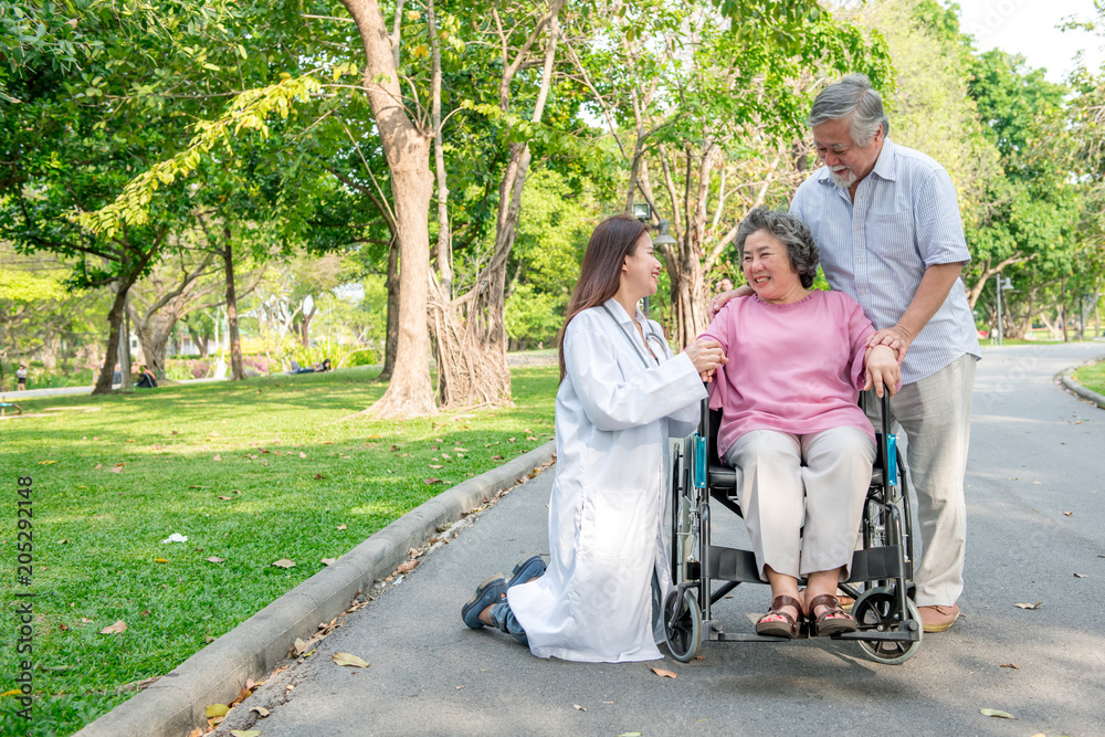 Nurse with senior patient in park. Senior disable woman in wheelchair relaxing and being comfort by a chinese female nurse. Nurse with senior patient in park. Senior disable woman in wheelchair relaxing and being comfort by a chinese female nurse.