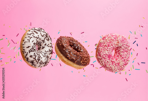 Flying sweet donuts isolated on pink background.
