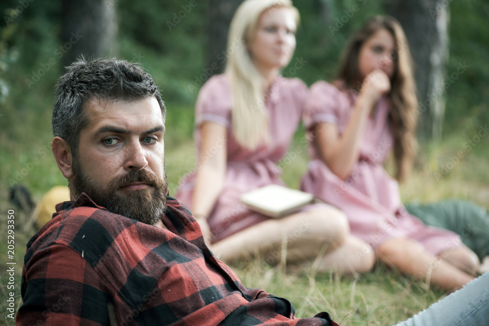 Bearded man with blue eyes spending time with friends outdoors. Closeup handsome man in lumberjack shirt lying on glass in woods. Outdoor recreation and nature concepts Bearded man with blue eyes spending time with friends outdoors. Closeup handsome man in lumberjack shirt lying on glass in woods. Outdoor recreation and nature concepts