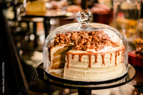 Caramel cake under glass bell dome. Cake stand, dessert buffet, storage © Iuliia
