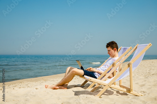 Young man with laptop on beach
