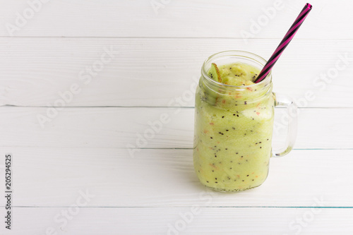 Healthy green smoothie with kiwi, apple and spinach in jar glass on white rustic wooden background. Copy space for text and design