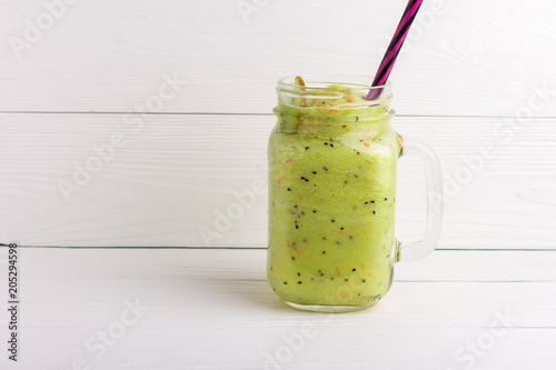 Healthy green smoothie with kiwi, apple and spinach in jar glass on white rustic wooden background. Copy space for text and design