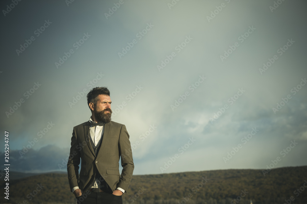 Hipster with beard and mustache on unshaven face. Bearded man on cloudy sky. Fashion businessman wear classic coat with bow tie. Freedom and success. Vacation travelling and wanderlust, copy space Hipster with beard and mustache on unshaven face. Bearded man on cloudy sky. Fashion businessman wear classic coat with bow tie. Freedom and success. Vacation travelling and wanderlust, copy space