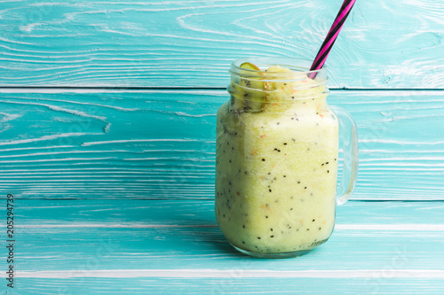 Healthy green smoothie with kiwi, apple and spinach in jar glass on blue rustic wooden background. Copy space for text and design