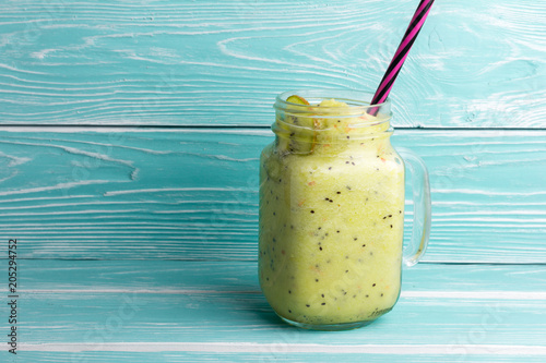 Healthy green smoothie with kiwi, apple and spinach in jar glass on blue rustic wooden background. Copy space for text and design