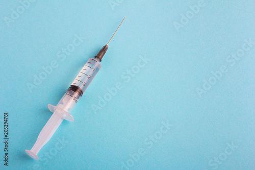 Syringe on blue background. Copy space