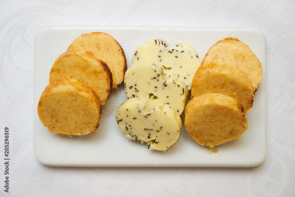 Butter flavored with herbs and spices on ceramic cutting board, close-up. 
