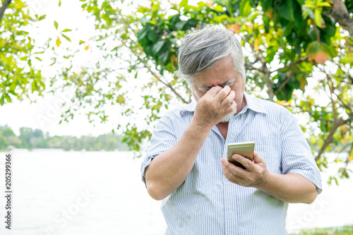 Canvas Print Senior man trying to use a mobile device