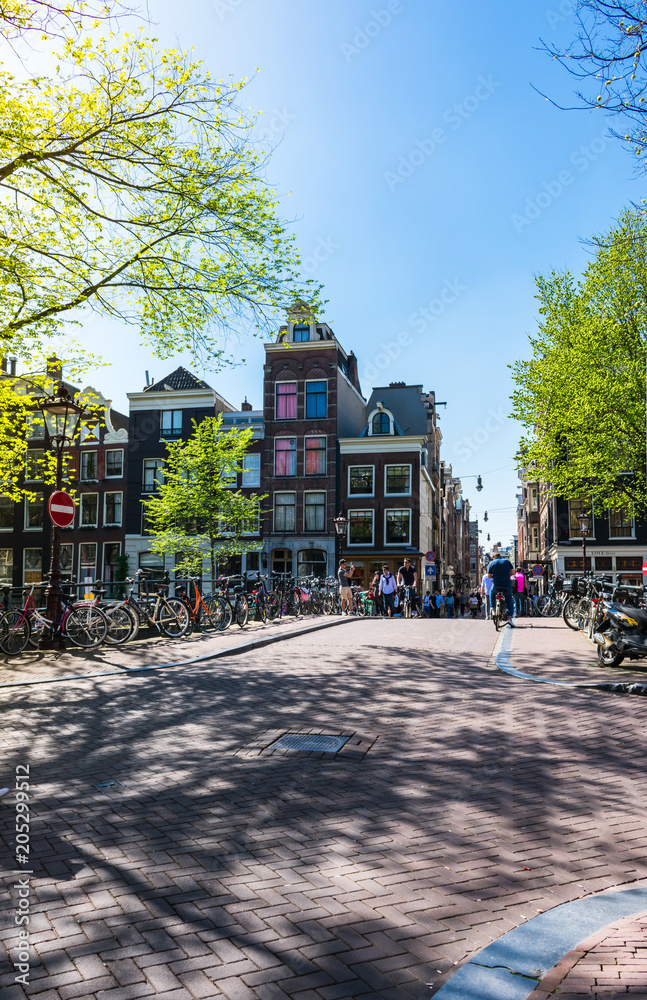 View of a lively square near a bridge over the Amstel river canal in Amsterdam on a bright and sunny spring day