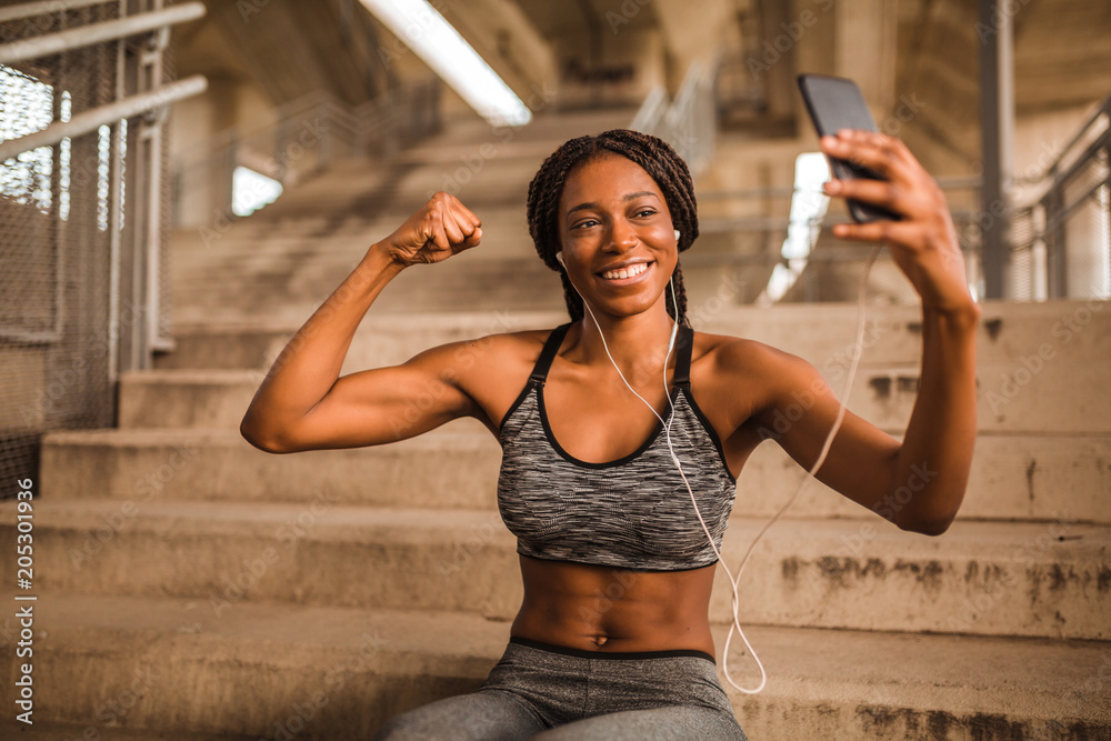 Young african american woman in sportswear sitting on stairs and taking  selfie with smartphone Stock Photo | Adobe Stock