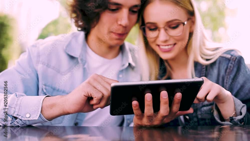 Young charming couple using tablet while sitting side by side Young charming couple using tablet while sitting side by side
