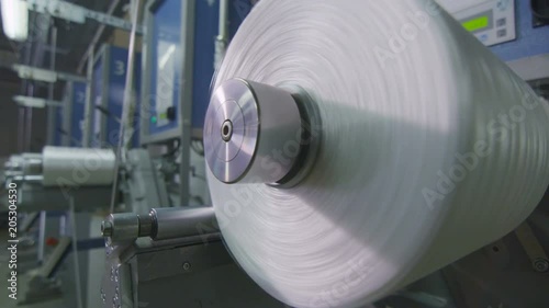 closeup glass threads wind on huge metal bobbin photo