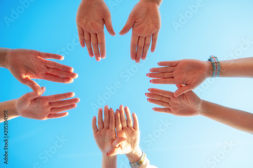 Hands of young people stretching to the center on beach