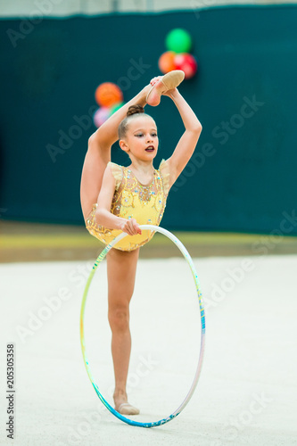 Beautiful little active gymnast girl with her performance on the carpet