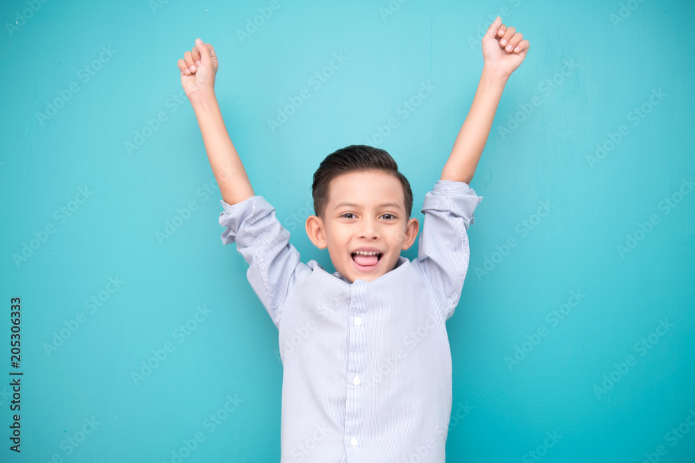 Young boy isolated in blue. Handsome early teenage boy portrait. Happy smile winning pose. Young boy isolated in blue. Handsome early teenage boy portrait. Happy smile winning pose.
