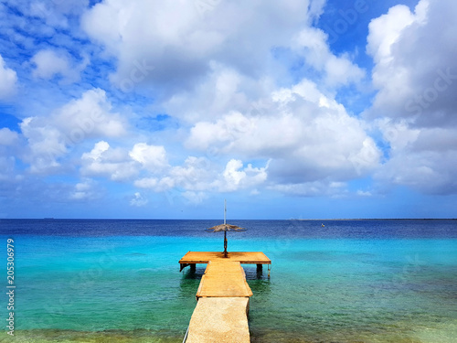 beautiful view of the sea in bonaire with a deck or harbor blue sky and clouds and some boats