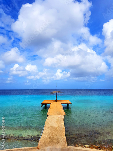 beautiful view of the sea in bonaire with a deck or harbor blue sky and clouds and some boats photo