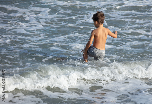 unknown boy having fun and playing in the waves at the beach