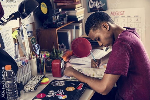 Teenage boy in a bedroom doing work stressed out and frustrated photo