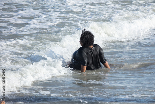 unknown woman is having fun in the waves of the ocean