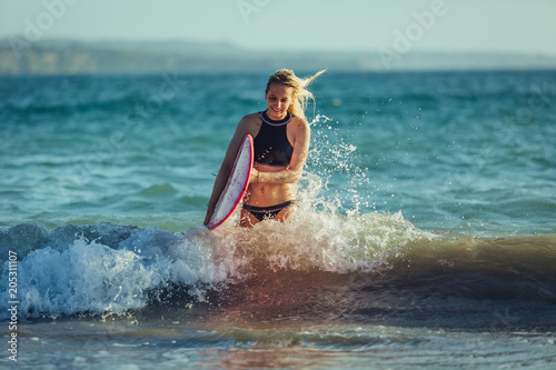 blonde female surfer with surfboard in water
