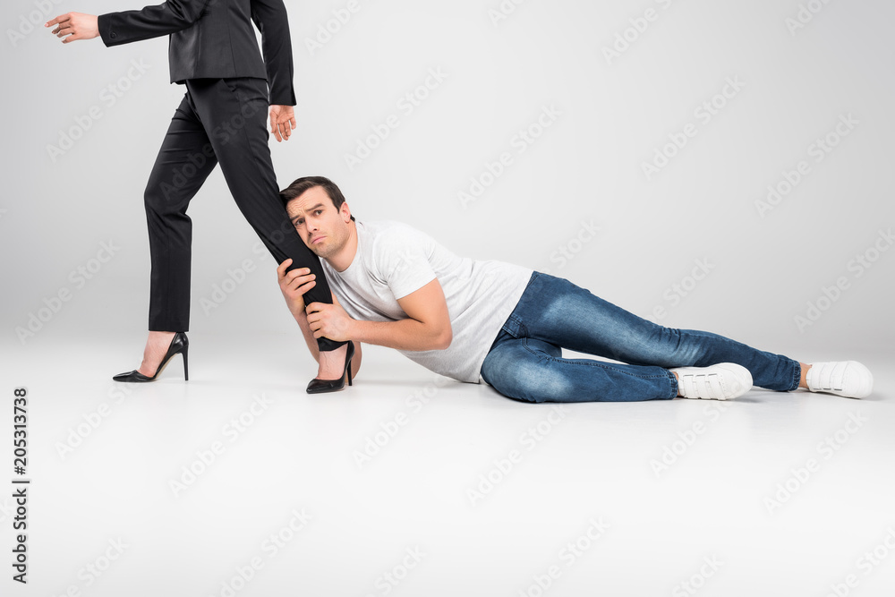Obraz premium husband holding leg of his business wife, feminism concept, isolated on grey