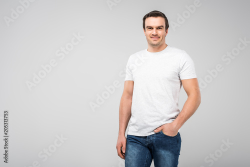 smiling handsome man with hand in pocket, isolated on grey