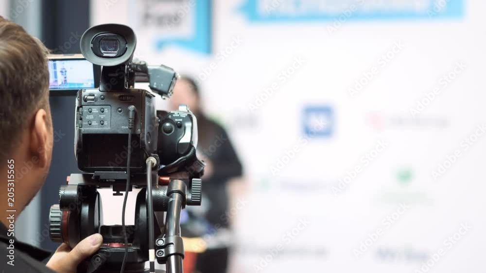 videocamera keeps record of performance of lecturer in presentation hall.