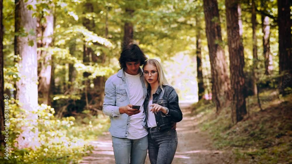 Young Couple Using Smartphone While Walks Through Forest Young Couple Using Smartphone While Walks Through Forest